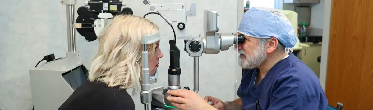 Dr. Michael Rom examining a patient at the slit lamp — banner photo from the current new patient forms page