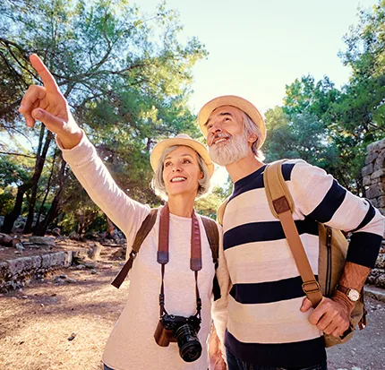 An active older couple hiking, one pointing into the distance