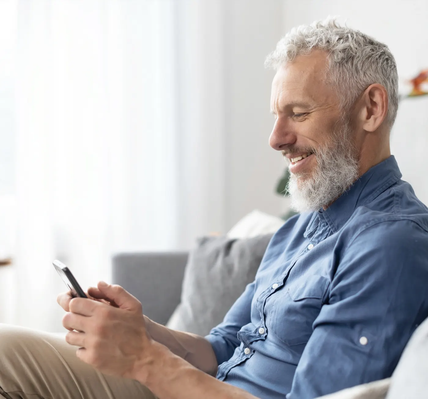 A man at home reading his phone without glasses