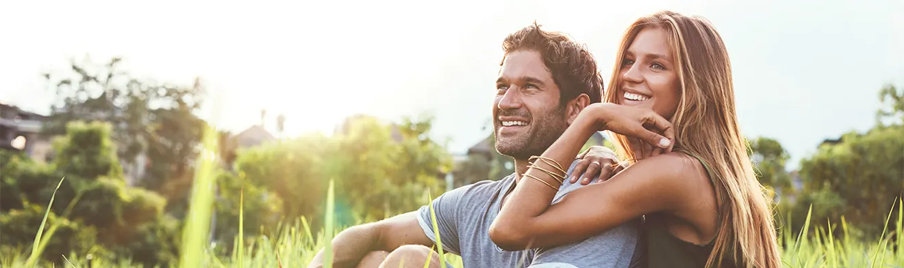 A young couple relaxing on the grass on a sunny day — banner photo from the current toric lens page